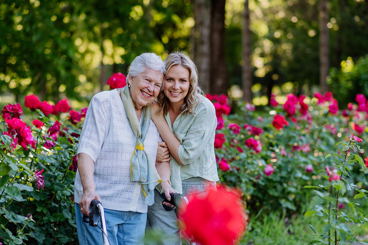 adult granddaughter with senior grandmother on walk in park